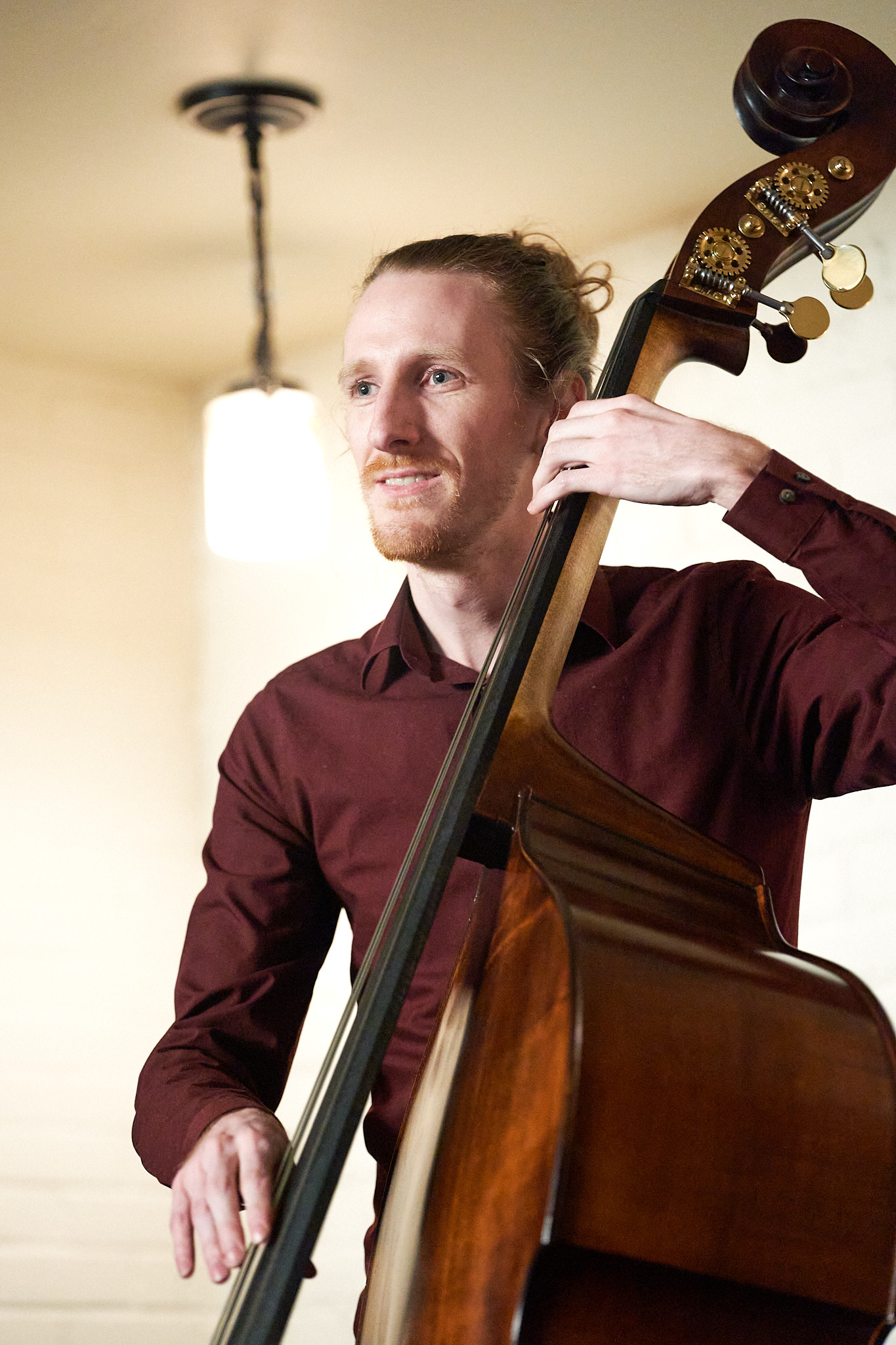 Another photo of Sam performing, a different angle, showing a lamp hanging from the 
								ceiling.